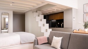 A modern living room with a sofa, a round glass table, and a bed with a white headboard. - Limehome Porto Rua 31 de Janeiro (Porto)