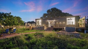 Una cabaña moderna de un solo piso con terraza y zona de estar exterior.