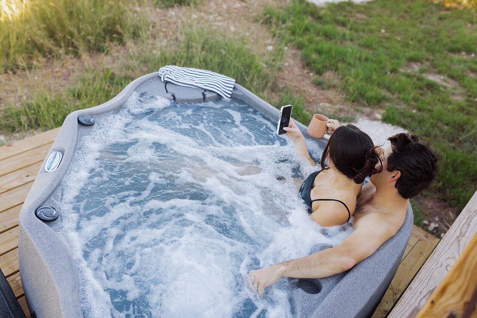 Ein Whirlpool mit zwei Personen, eine davon hält ein Smartphone.