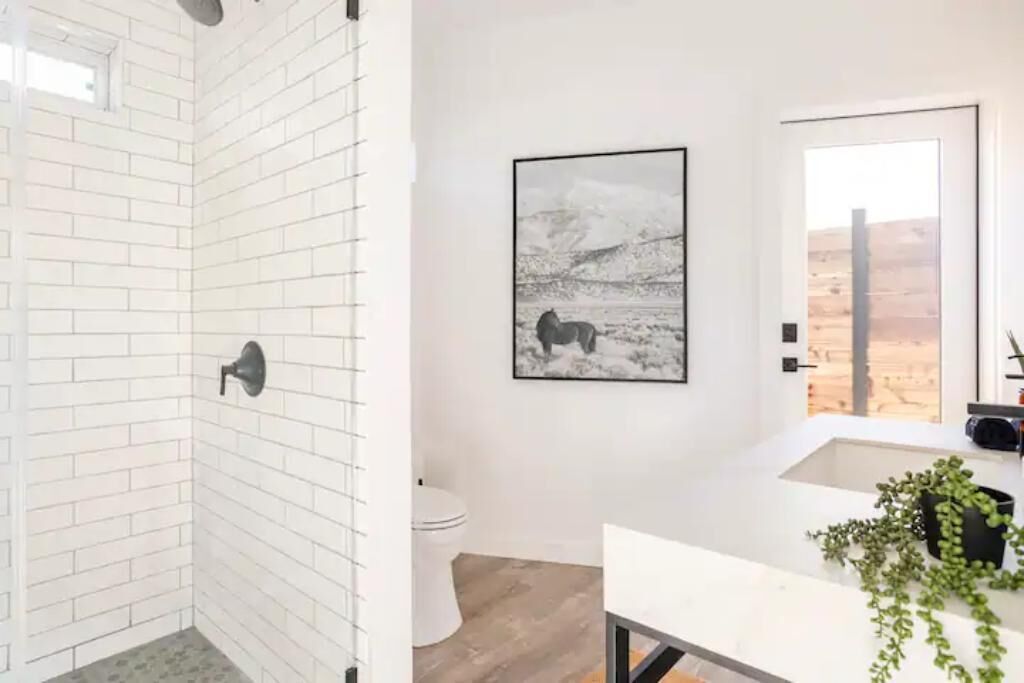 A bathroom with white brick walls, a white sink, and a framed picture of a horse on the wall.