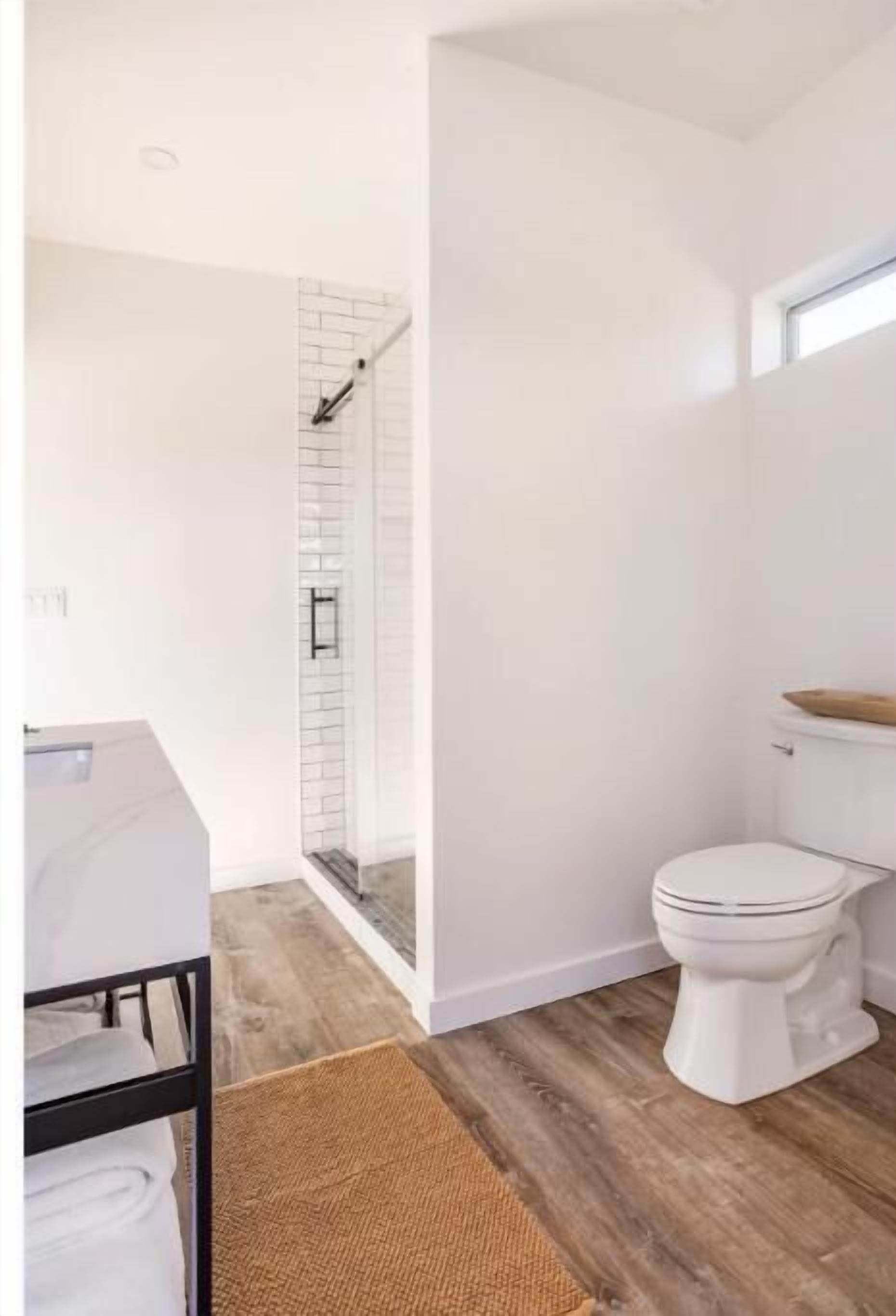 Une salle de bain moderne avec douche, toilettes et plancher en bois.