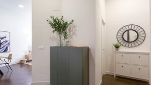 Un intérieur moderne avec un meuble gris, un miroir rond et une petite plante en pot.