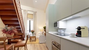 A modern kitchen with a microwave, coffee maker, and a dining area with wooden chairs and a table.