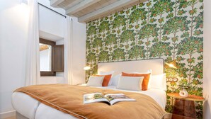 Un dormitorio con cama, mesita de noche y pared con estampado floral.