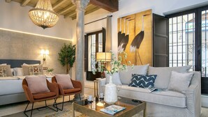 A modern living room with a sofa, armchairs, a coffee table, and a chandelier. - Genteel Home Horno Marina 1 (Granada)