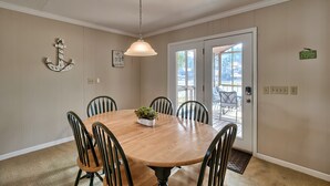 Un comedor con una mesa de madera, seis sillas, una lámpara colgante y una planta en maceta.