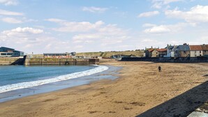 A beach with a sandy shore, a pier, and buildings in the background. - Doodles Holiday Home (Eyemouth)