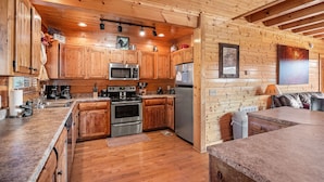 A wooden cabin-style kitchen with built-in appliances, wooden cabinets, and a stone countertop. - 5-Bedroom Mountain Lodge with Views and Games (PIGEON FORGE)