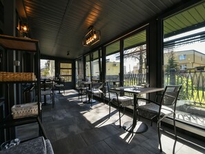 An outdoor café with tables and chairs, large windows, and a metal ceiling. - Willa Marcel Park (Busko-Zdroj)