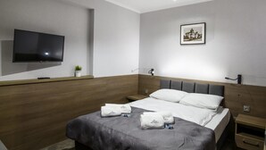 A modern hotel room with a large bed, a flat-screen TV, a framed picture on the wall, and a small plant on the nightstand. - Willa Marcel Park (Busko-Zdroj)