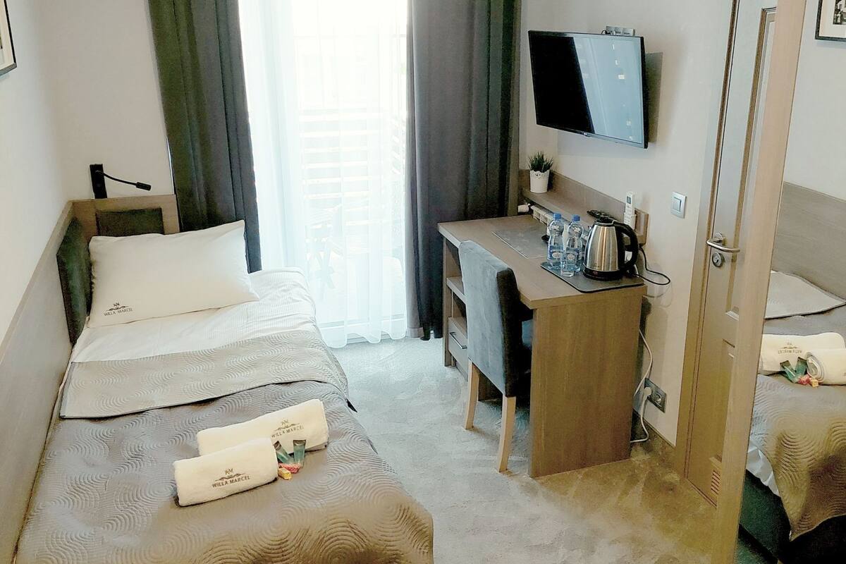 A hotel room with two beds, a desk, a television, and a window with curtains.