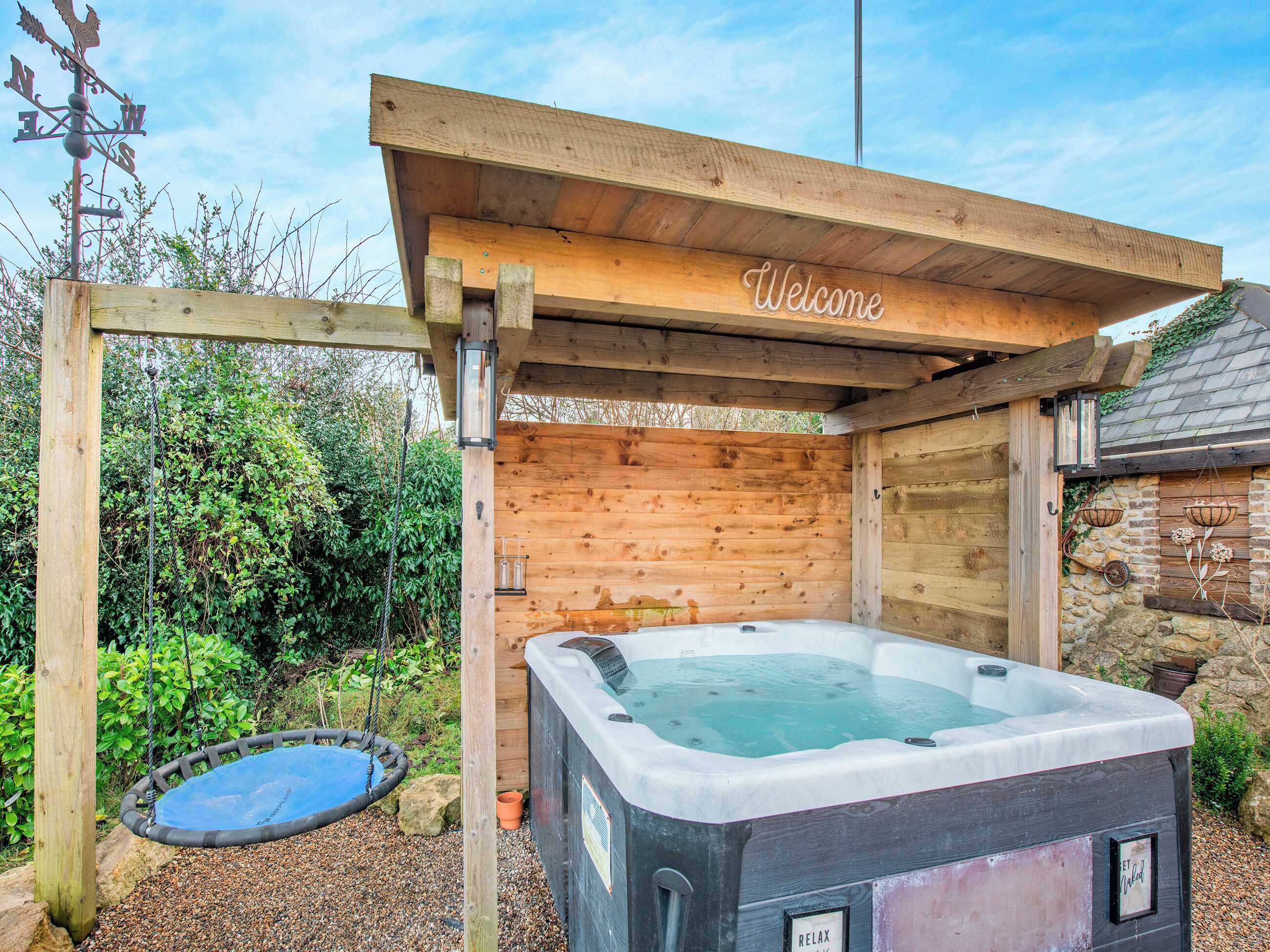 Eine Holzkonstruktion mit Whirlpool und Schaukel, umgeben von viel Grün.