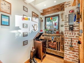 A room with a brick wall, a wooden desk with vintage items, framed pictures, and a window with a view of trees. - 2 bedroom accommodation in Otham, near Maidstone (Otham, near Maidstone)