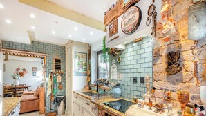 Una cocina con pared de piedra, barra y zona de comedor con sofá y mesa.