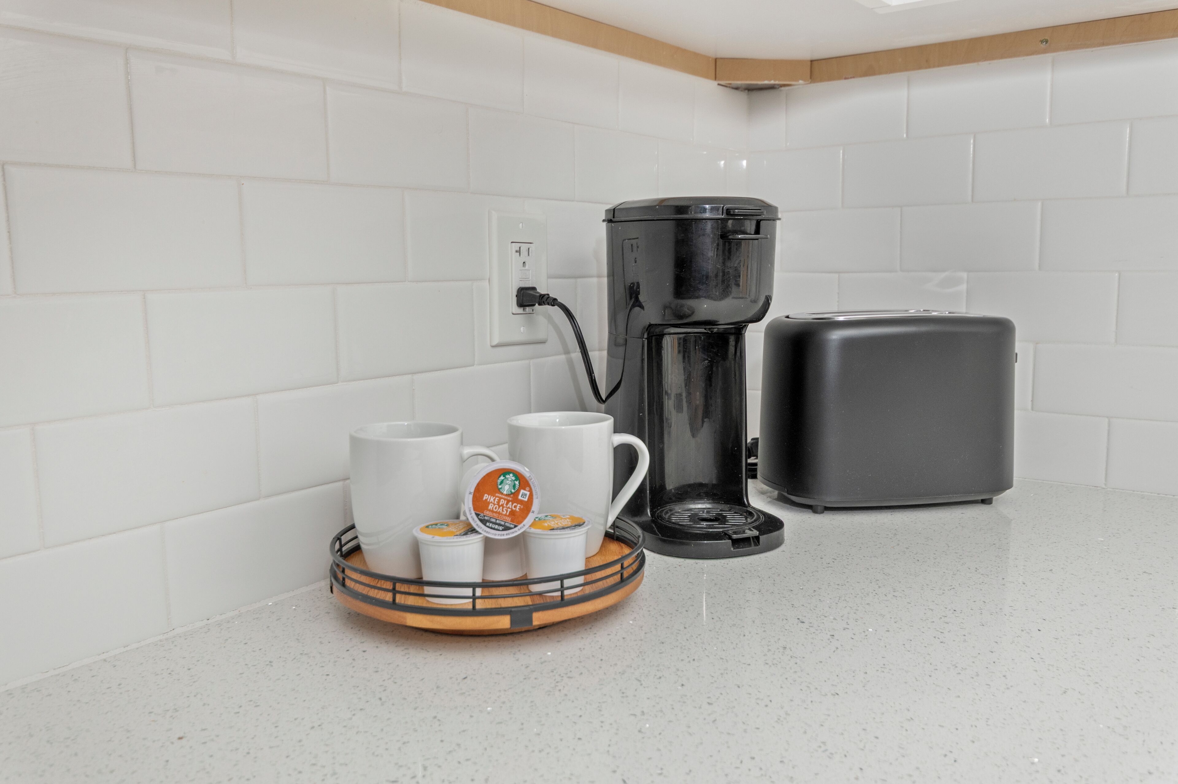 A kitchen with a coffee maker, a toaster, and a tray with coffee cups.