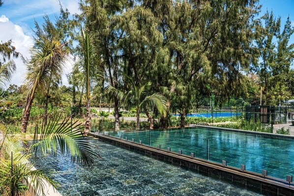 A rectangular pool surrounded by tropical vegetation and trees.