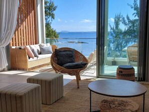 Un balcon avec un canapé en osier, une table ronde et une chaise en osier.