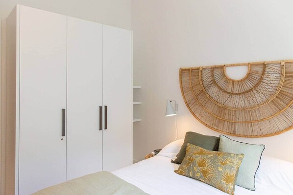 A bedroom with a bed, pillows, a wall-mounted lamp, and a wardrobe.
