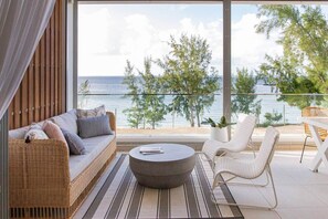 Ein Balkon mit einer Couch, Stühlen und einem Tisch, mit Blick auf einen Strand und das Meer.