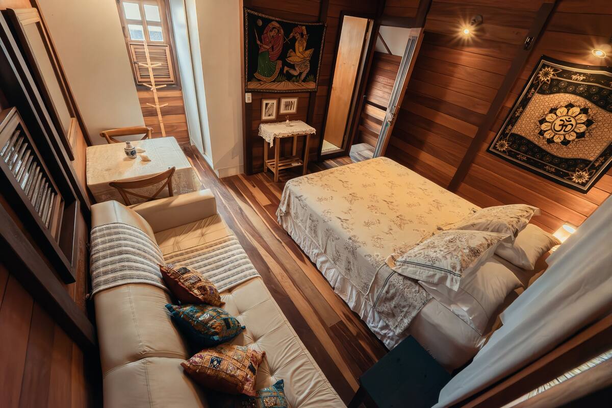 Une pièce confortable avec un lit, un canapé, une petite table et un tableau au mur.
