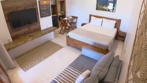 A modern bedroom with a large bed, a sofa, a TV, and a dining area. - Ankh Jeri (Jijoca de Jericoacoara)