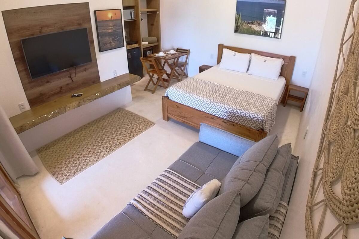Une chambre moderne avec un grand lit, un canapé, une télévision et un coin repas.