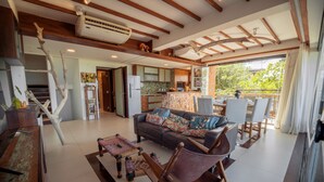 A spacious living area with a sofa, chairs, a dining table, and a kitchen in the background. - Ankh Jeri (Jijoca de Jericoacoara)