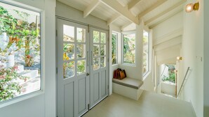 A bright hallway with white walls, a wooden ceiling, and large windows offering views of greenery. - Luxury Sunset Pool Villa - Koh Phangan (Surat Thani)