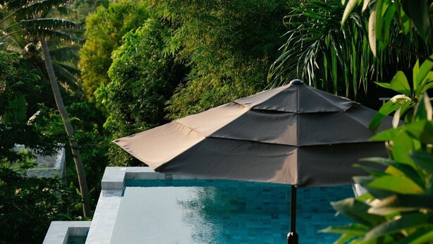 An infinity pool with a wooden deck, lounge chairs, and an umbrella. - Luxury Sunset Pool Villa - Koh Phangan (Surat Thani)