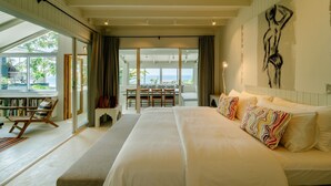 A spacious bedroom with a large bed, a view of the outdoors, and a dining area with chairs and a table. - Luxury Sunset Pool Villa - Koh Phangan (Surat Thani)