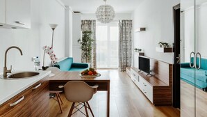A modern kitchen with a dining area, a TV, and a sofa. - DD Apartments (Cluj-Napoca)