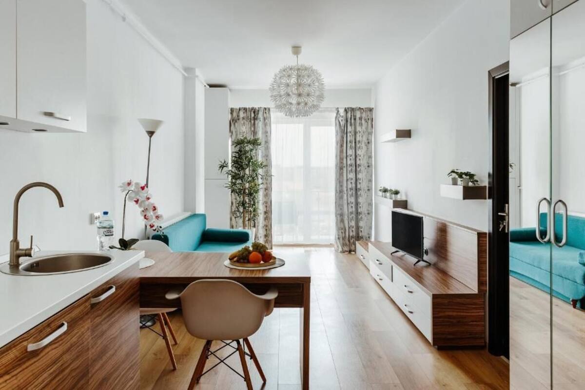 A modern kitchen with a dining area, a TV, and a sofa.