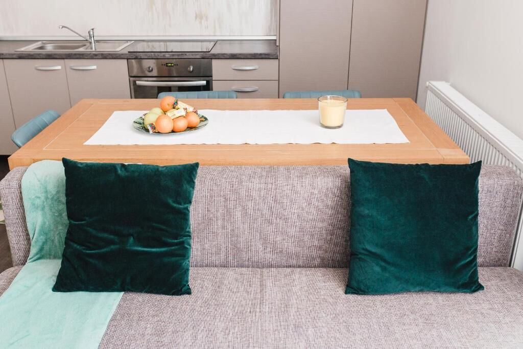 Une cuisine moderne avec une table à manger dressée pour deux personnes, un saladier de fruits et une bougie.