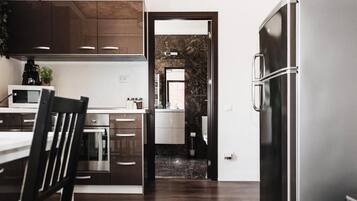 A modern kitchen with dark wooden cabinets, a stainless steel refrigerator, and a marble backsplash.