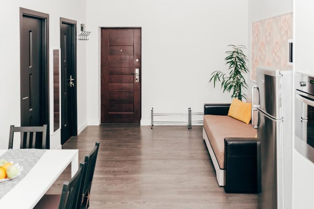 Una cocina moderna con comedor, un sofá con un cojín amarillo y una planta.