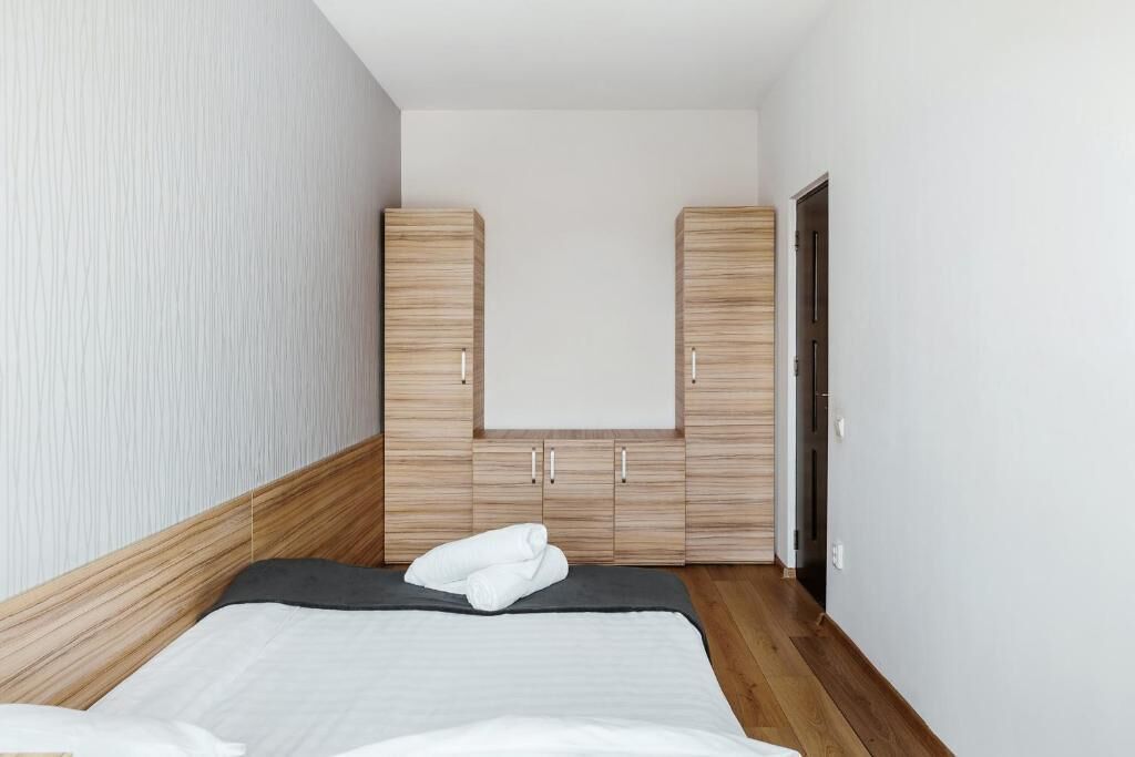 Quarto com cama, guarda-roupa de madeira e uma porta.