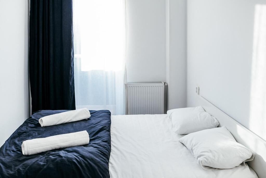 A hotel room with a bed, white pillows, a dark blue bedspread, and a white radiator.