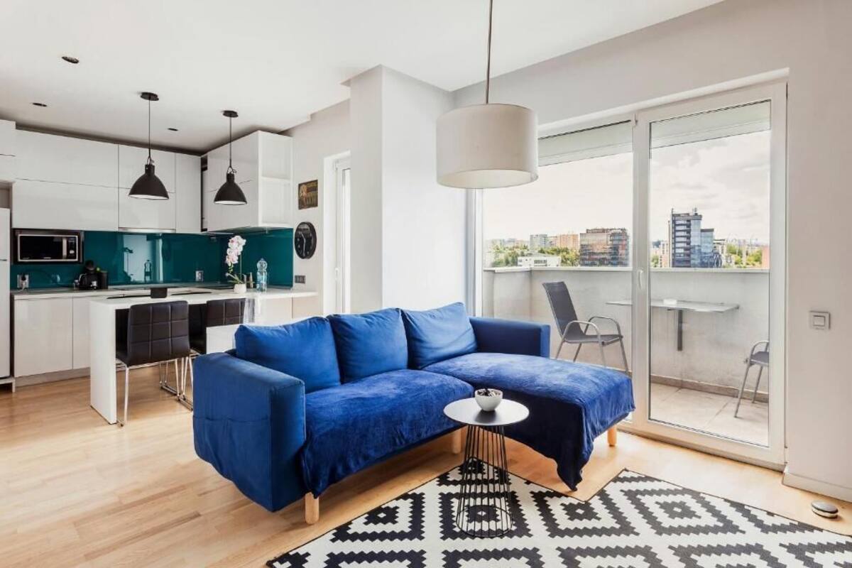 A modern living space with a blue sofa, a small round table, and a patterned rug.