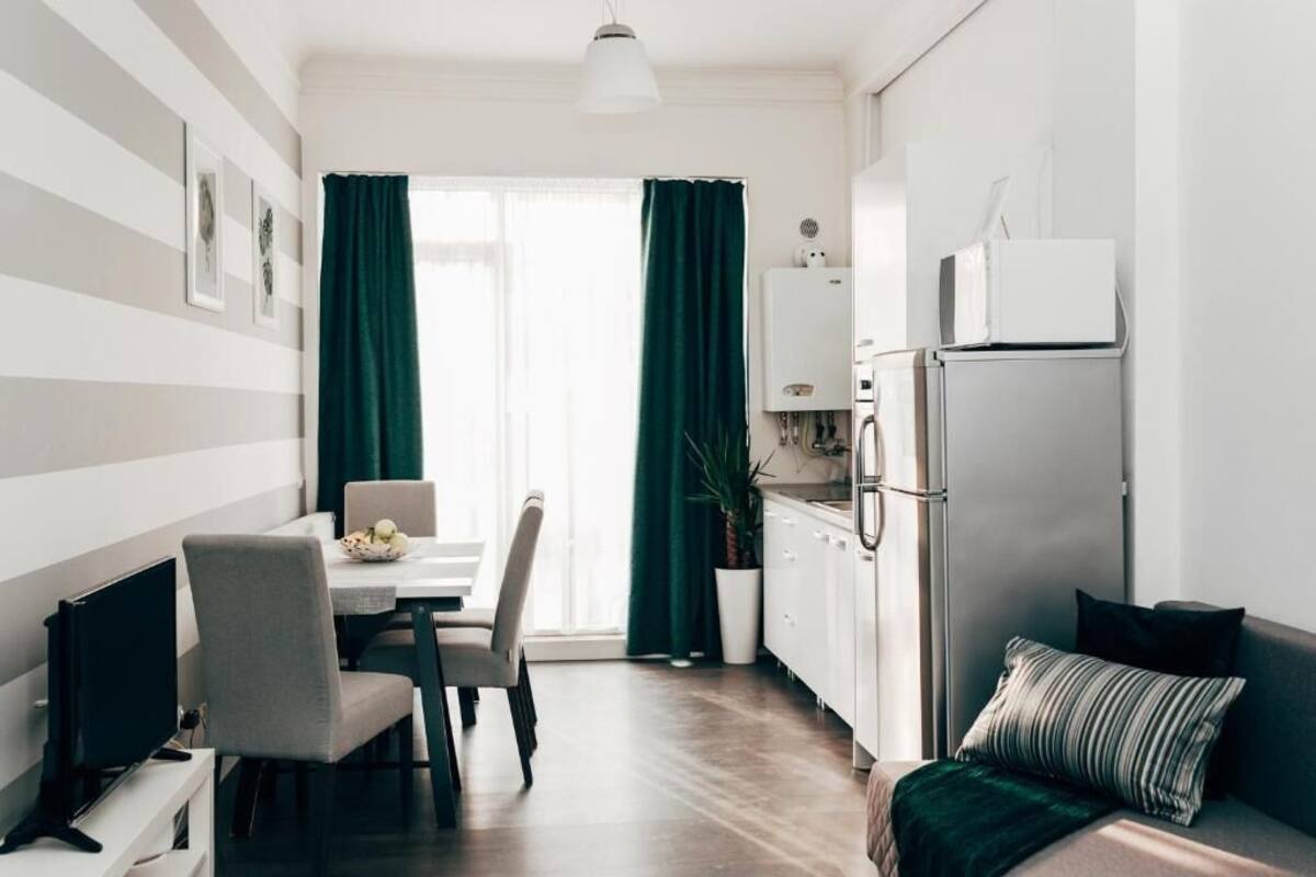 A compact living space with a dining area, kitchenette, and a bed.