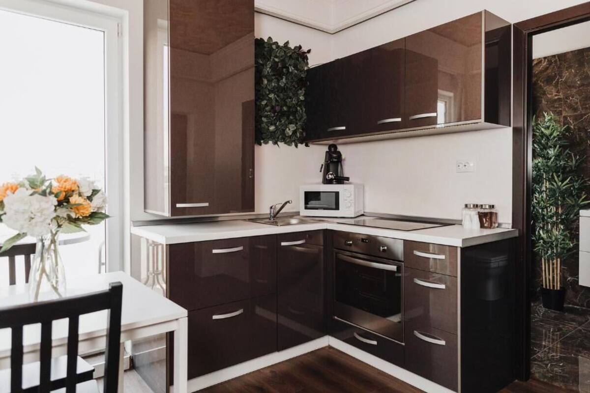 A modern kitchen with dark brown cabinets, a white countertop, a built-in microwave, and a coffee maker.