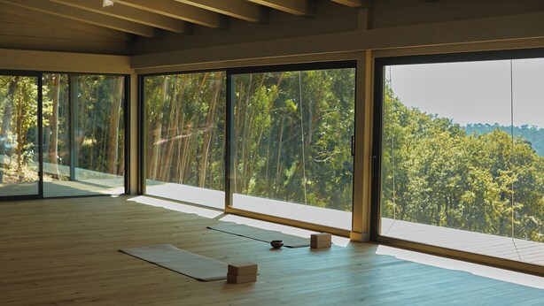 Una habitación amplia con ventanas grandes que dan a una zona boscosa.