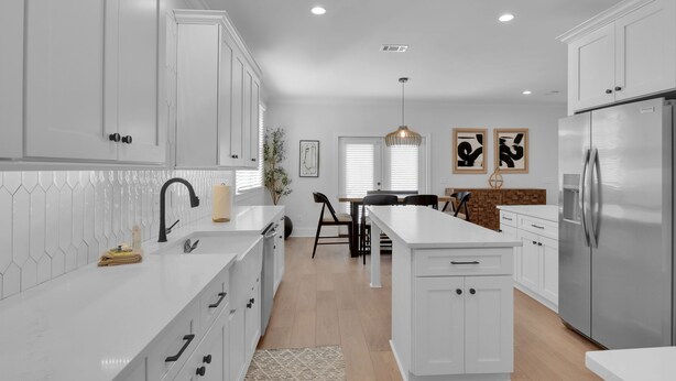 A modern kitchen with white cabinetry, a stainless steel refrigerator, and a central island. - Beautiful 4 bedroom home with a pool! (Saint Simons Island)