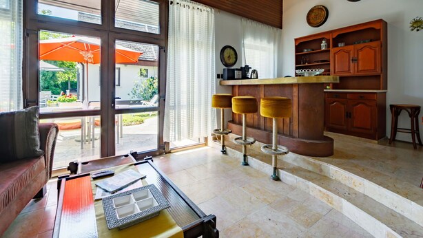 A spacious living area with a wooden ceiling, a kitchen with wooden cabinets, and a dining area with a table and chairs. - Beautiful  villa for 8 people with WIFI, TV, terrace and pets allowed (Marcali)