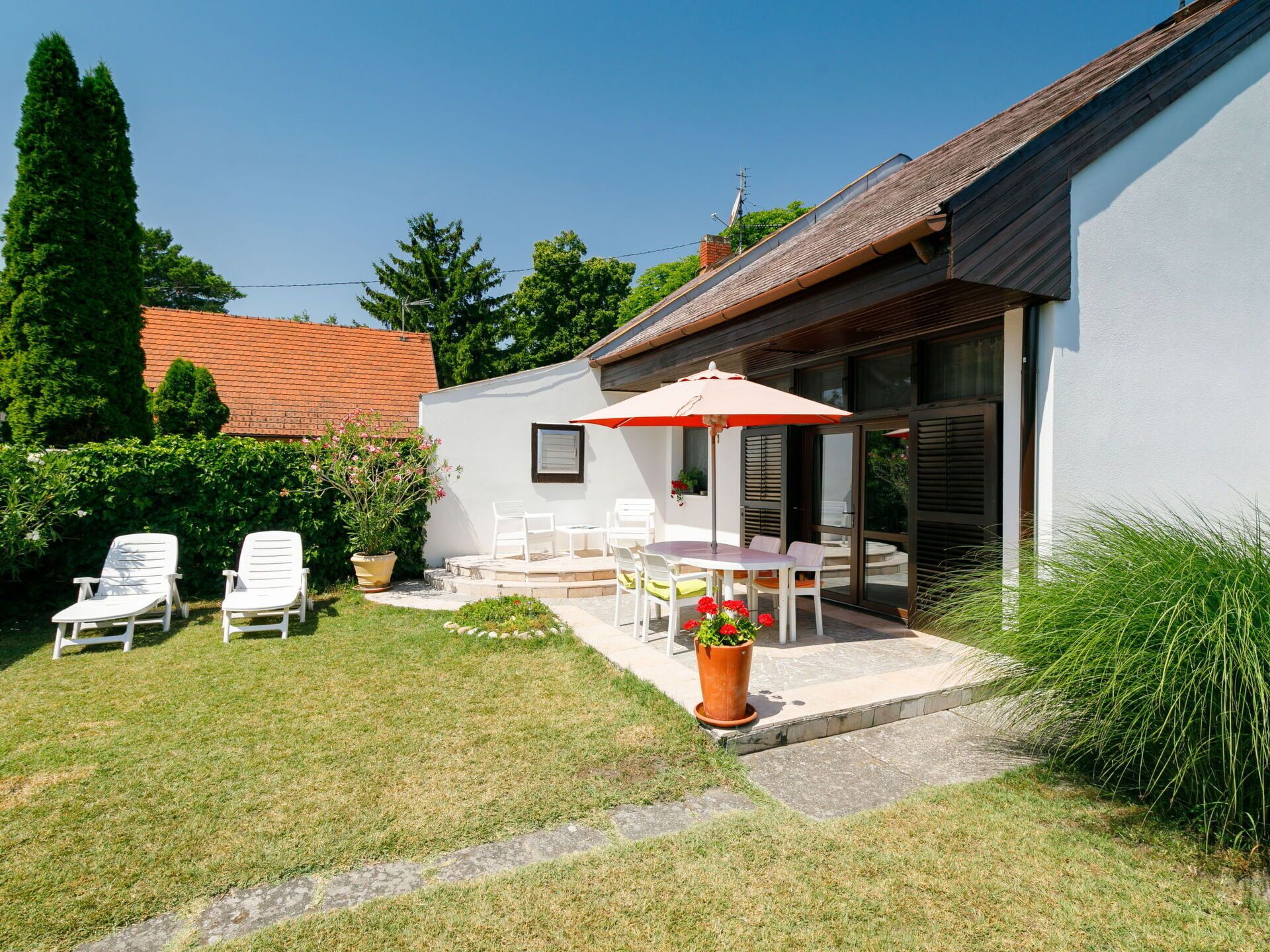 Une maison moderne dotée d’un patio aménagé avec du mobilier d’extérieur et une grande plante en pot.