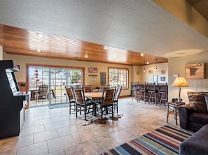 A spacious indoor area with a dining table and chairs, a fireplace, and a large window overlooking a deck.