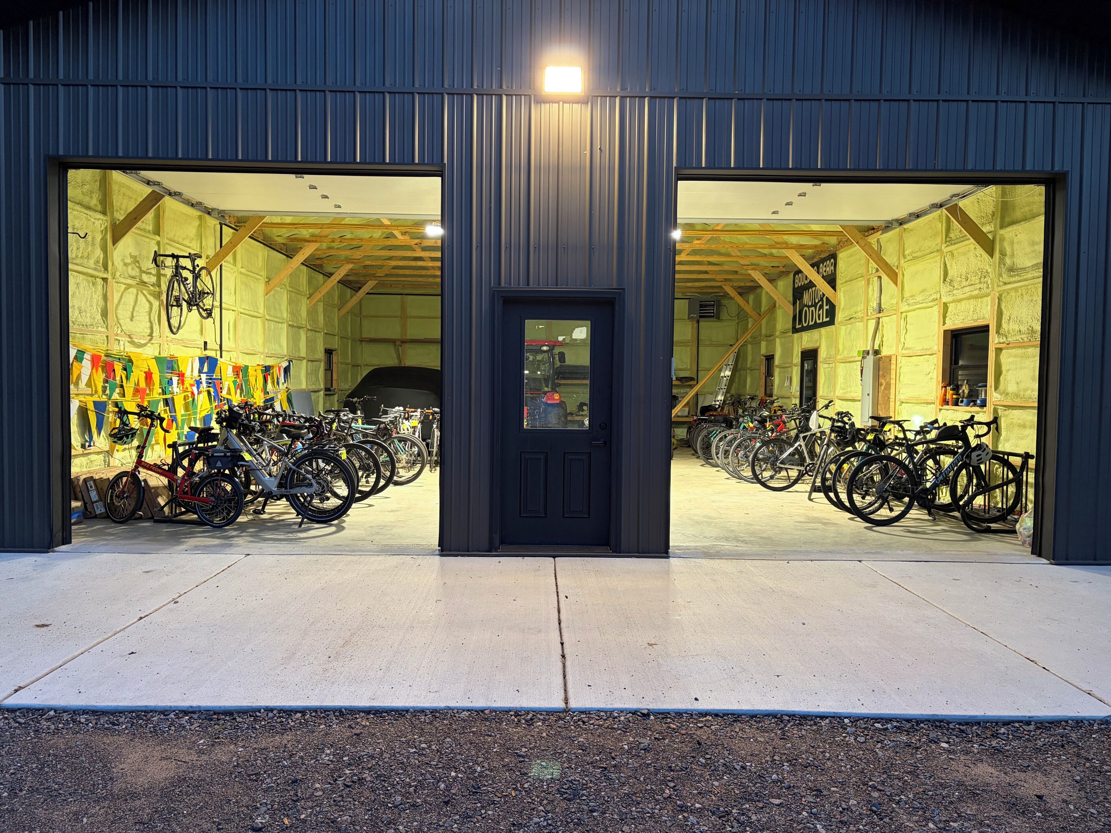 A building with two large open doors, a row of bicycles inside, and a sign that reads 'Bike Motor Lodge'.