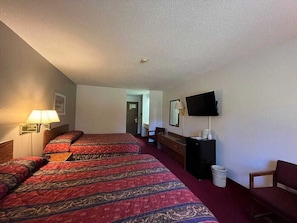 A hotel room with two beds, a TV, a desk, and a chair.