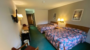 A hotel room with two beds, a desk, a chair, a trash bin, and two wall-mounted lamps. - Boulder Bear Motor Lodge (Boulder Junction)
