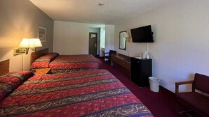 A hotel room with two beds, a TV, a desk, and a chair.