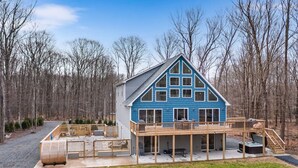 A blue house with a deck, surrounded by trees.